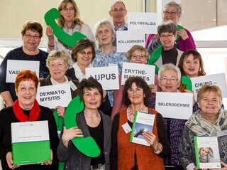 Gruppenfoto mit Schildern auf denen Krankheiten stehen Treffen seltene Erkrankungen