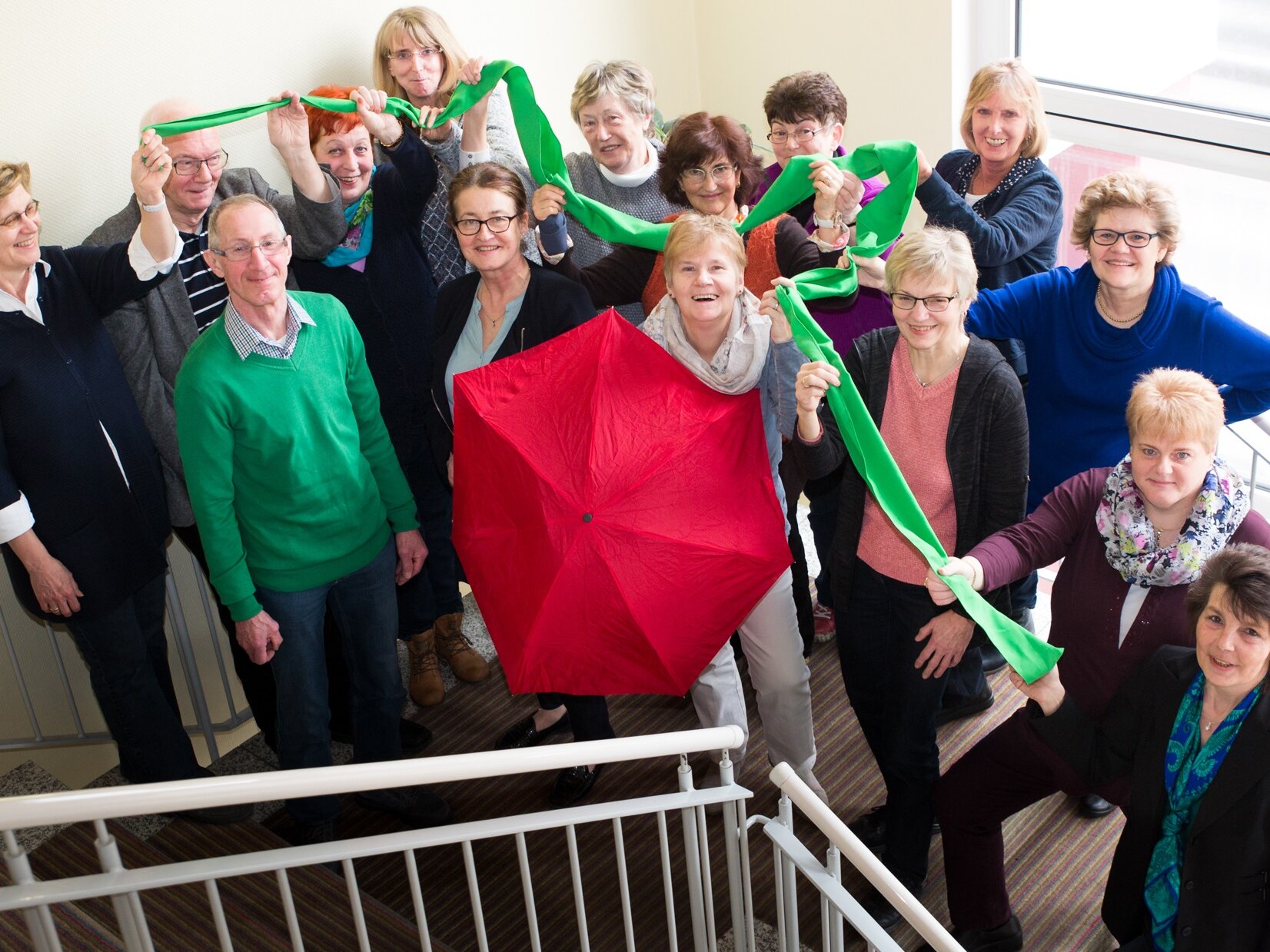 Gruppenbild in Treppenhaus mit Gymnastikband und rotem Schirm